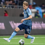 A dynamic action shot of the Swedish winger accelerating past defenders in a Djurgårdens IF jersey, embodying speed and skill.