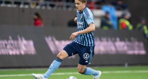 A dynamic action shot of the Swedish winger accelerating past defenders in a Djurgårdens IF jersey, embodying speed and skill.