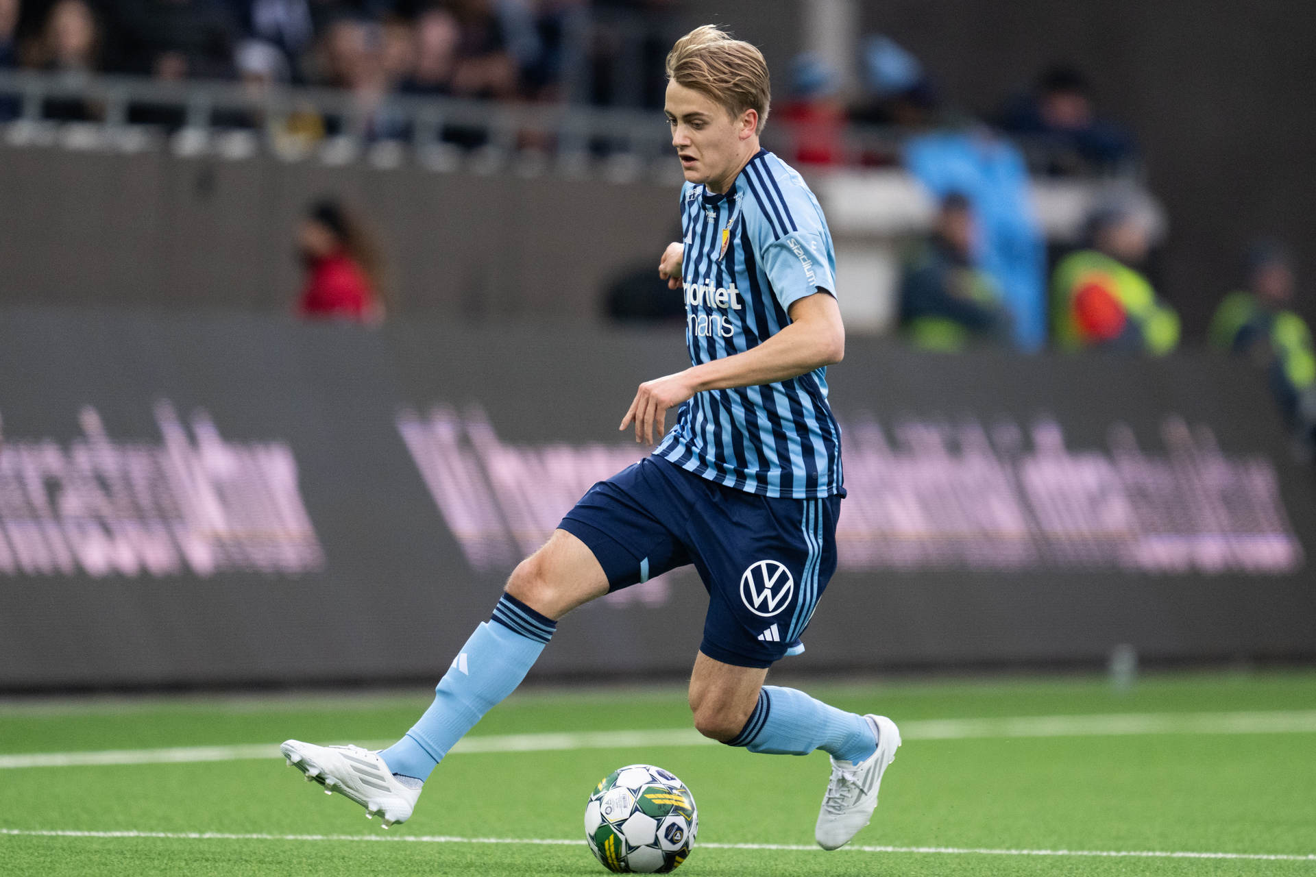 A dynamic action shot of the Swedish winger accelerating past defenders in a Djurgårdens IF jersey, embodying speed and skill.
